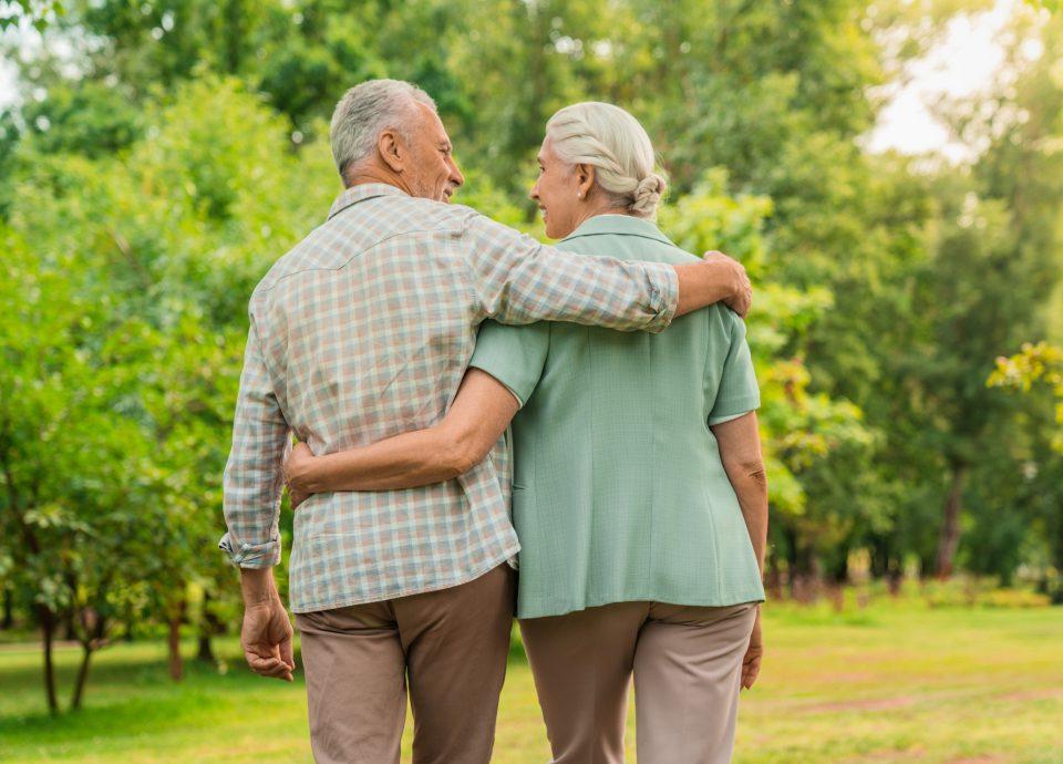 Senior couple walking outside with arms around each other